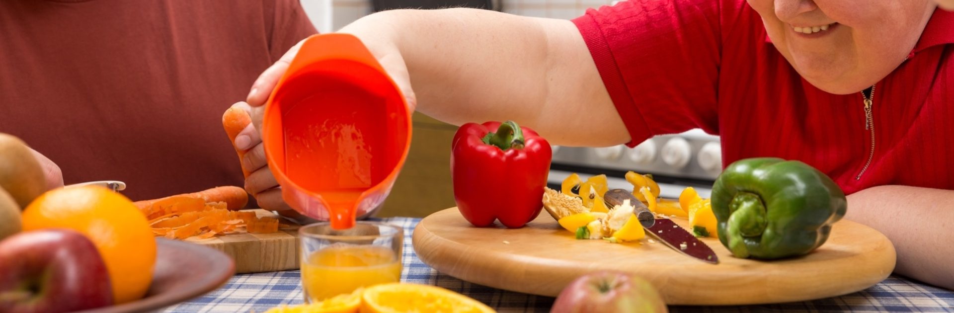 Geistig behinderte Frau mit Betreuern am Tisch mit viel Gemüse und Obst